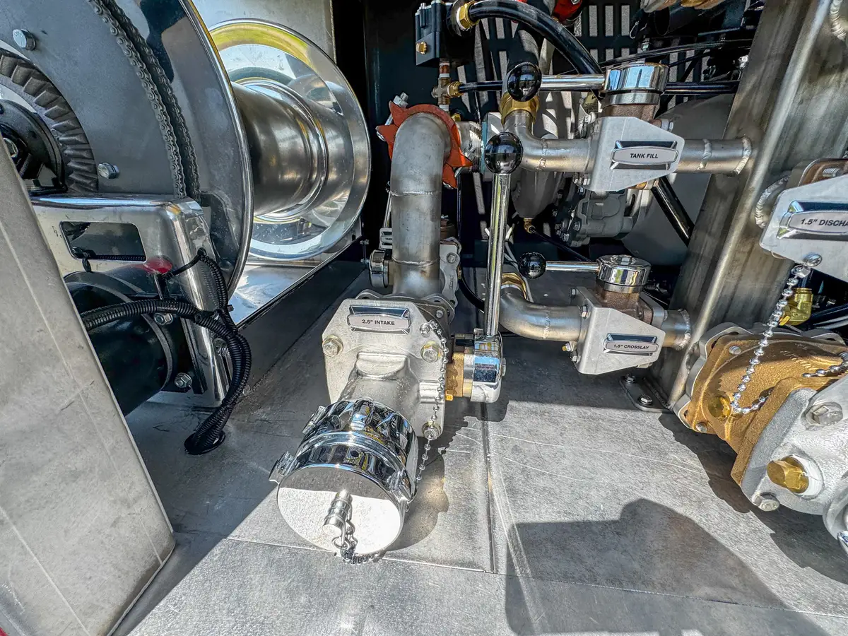 Rear pump-system close-up with manifold, hoses, and control hardware.